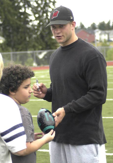 University of Washington quarterback Jake Locker signs a football during the Panther Future Champs Football Camp July 8 at Bonney Lake High School. Locker and teammate Cody Habben spoke to the campers about their football careers and also answered questions.