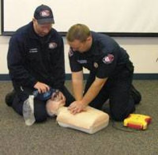 Paramedic Frank Gibbons (left) and firefighter Mike McGinnis demonstrate proper CPR technique.