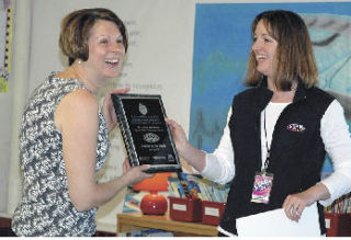 Kibler Elementary teacher Joan Jacobson receives a plaque from radio personality Corine McKenzie during Friday’s surprise celebration.