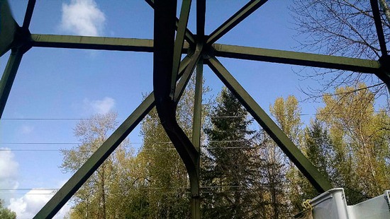 The damage to the bridge where the over-height load struck the bridge’s arched steel overhead support structure.