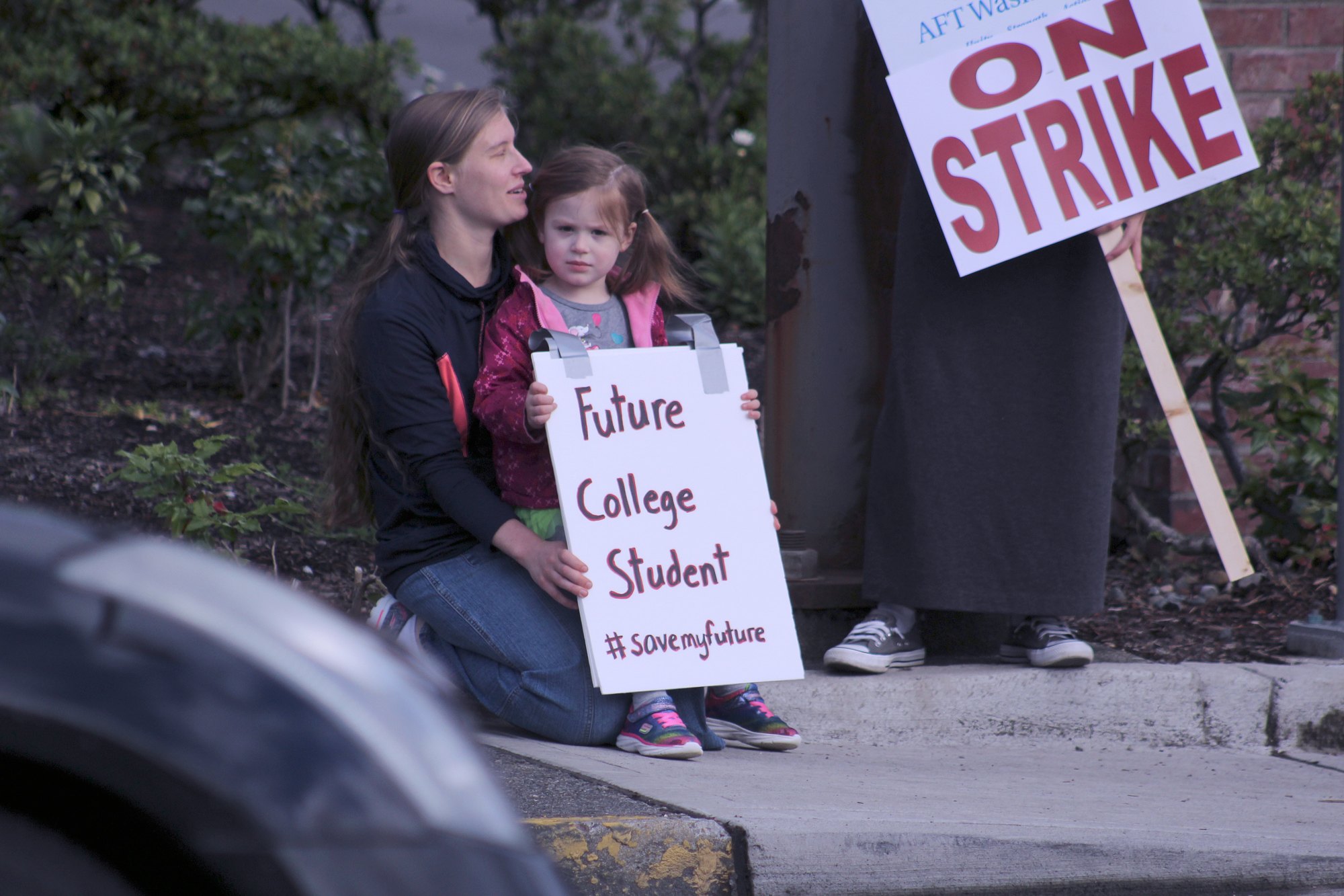 Kenzie and her mother Ashley join a dozen strikers outside the Enumclaw Green River College Campus today