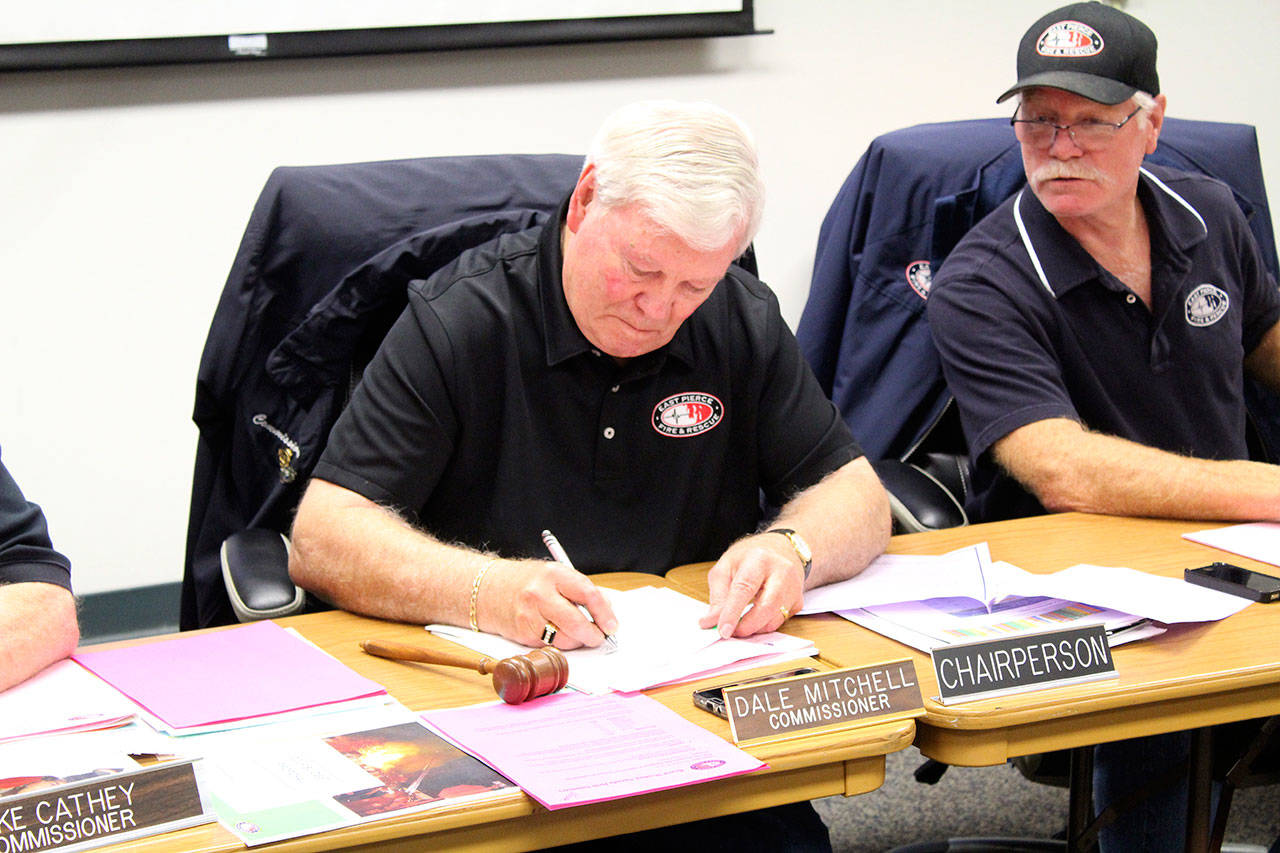 Fire Commissioner Chairperson Dale Mitchell and other commissioners sign a resolution giving authority to Chief Bud Backer to sign bond documents, meaning the commission doesn’t have to schedule a special meeting to do so themselves. Photo by Ray Miller-Still