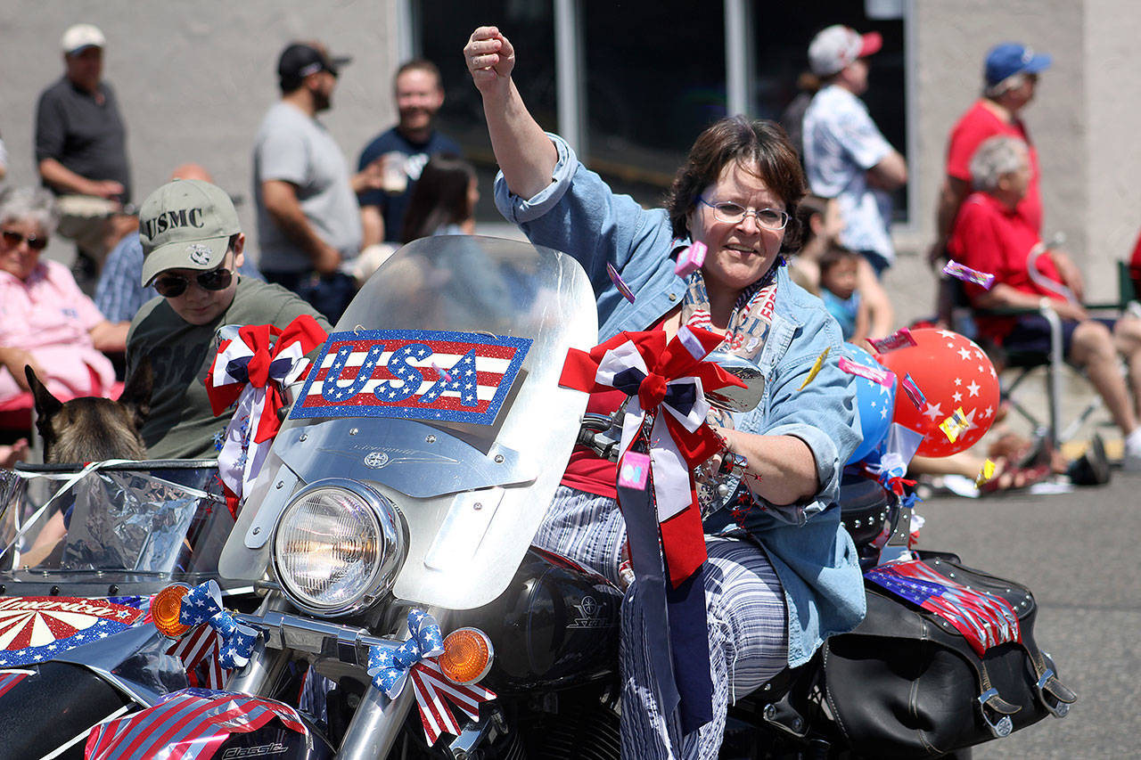 A woman in the 2017 Stars and Stripes Parade down Cole Street in 2017 throws candy to children along the route. File photo