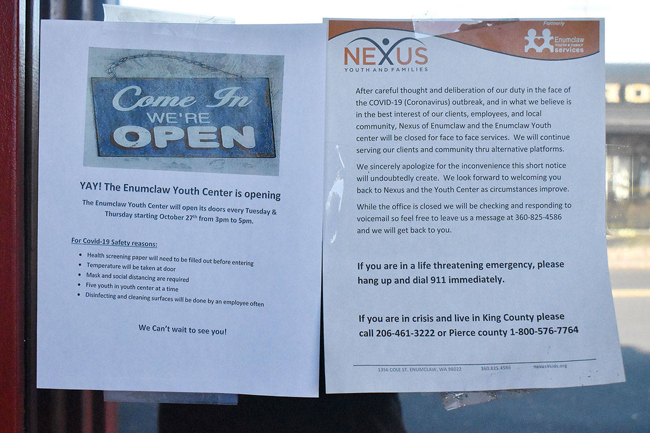 Two signs are found on the Enumclaw Youth Center window this week. The older, on the right, explains the center's March closure. The sheet on the left announces the center will now be open four hours per week. Photo by Kevin Hanson