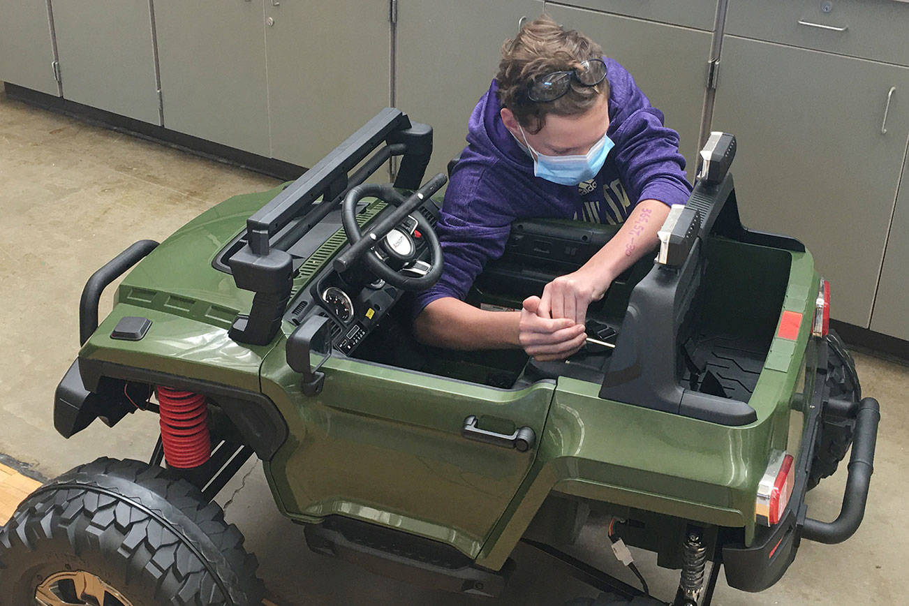 Enumclaw's Eli Murphy spent an estimated 75 hours modifying an electric car for a Colorado boy with special needs (pictured here). The local photos show Eli modifying the vehicle's seatbelt. Contributed photo