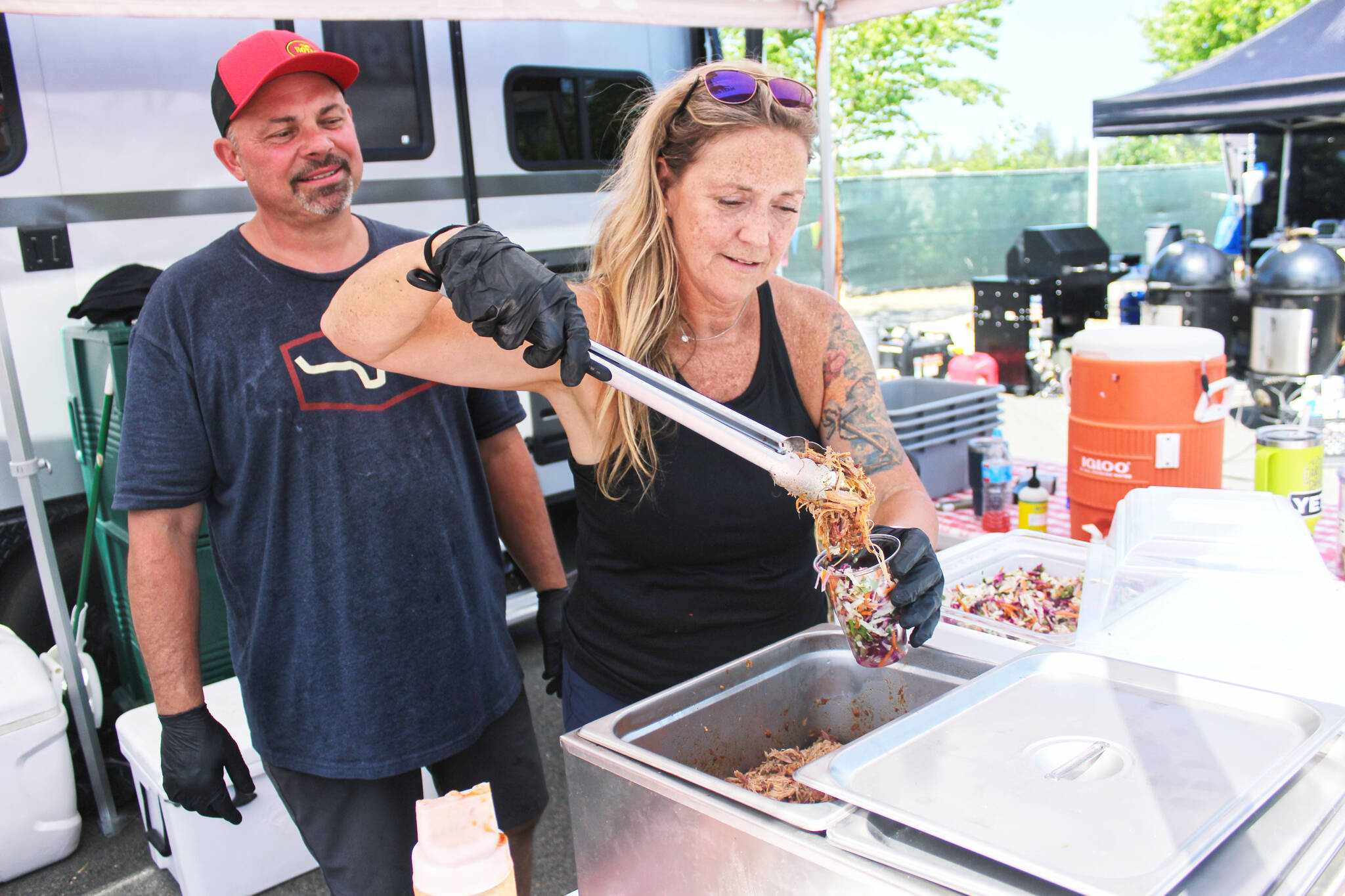 Ron Hedin and his boss Julie Ross, who is putting the finishing touches on Hoggin Da Sauce BBQ's famous Slaw Sundae. Photo by Ray Miller-Still