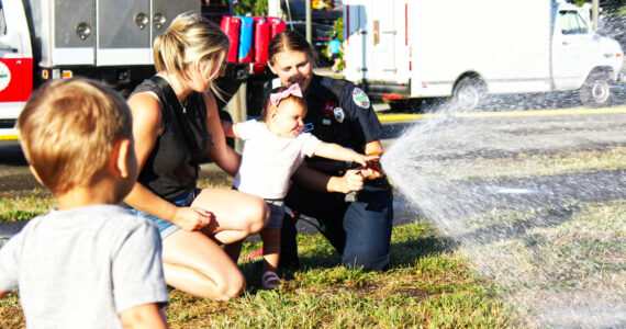 Photo by Ray Miller-Still
Myla Cannizzaro helping a Buckley firefighter with a hose for the splash zone during last year’s National Night Out event.