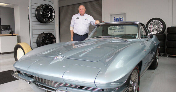 Alan Gamblin, who took over his father’s dealership in 1985, stands in his car shop next to his personal 1964 Corvette in 2019 while celebrating being 50 years in business on the Plateau. Photo by Ray Miller-Still