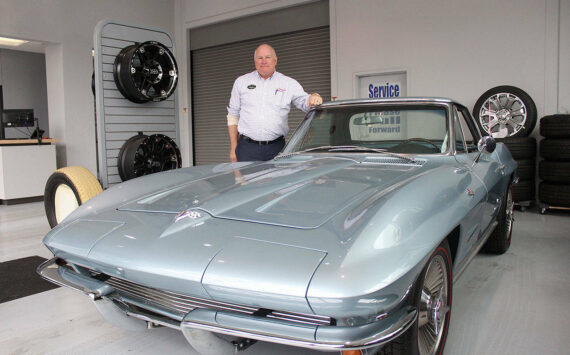 Alan Gamblin, who took over his father’s dealership in 1985, stands in his car shop next to his personal 1964 Corvette in 2019 while celebrating being 50 years in business on the Plateau. Photo by Ray Miller-Still