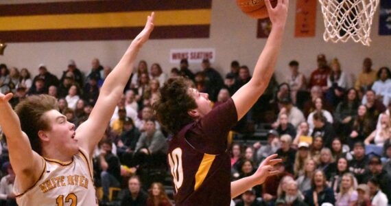 PHOTO BY KEVIN HANSON
Enumclaw High’s Gavin Trachte goes high for a layin during Friday night’s victory over visiting White River. Applying defensive pressure is Zach Wisdom (12).